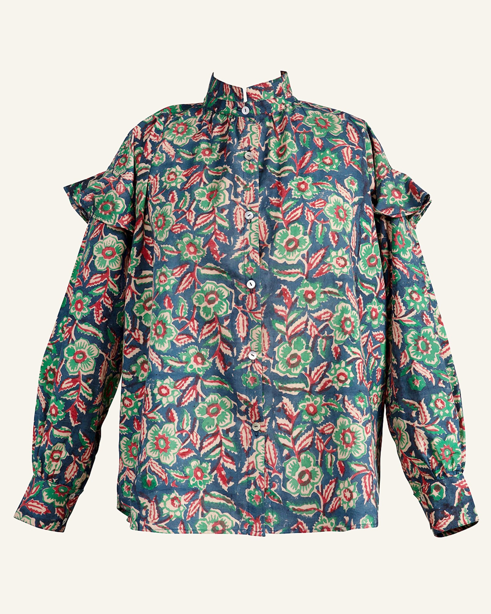 The Freya Flower Shirt is a long-sleeve blouse featuring a high collar and ruffled shoulder details, adorned with floral patterns. The fabric showcases green and red flowers alongside leafy designs set against a dark background.