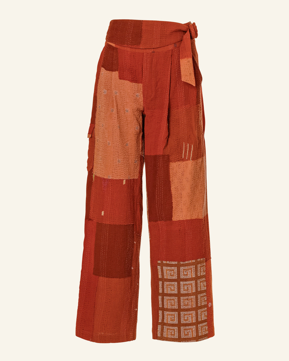 The Georgia Earth Kantha Pant is crafted from vintage saris in warm shades of red and orange, featuring geometric patterns and a tied waist. These bohemian-style pants boast wide legs and showcase the unique touch of handmade artisan craftsmanship.