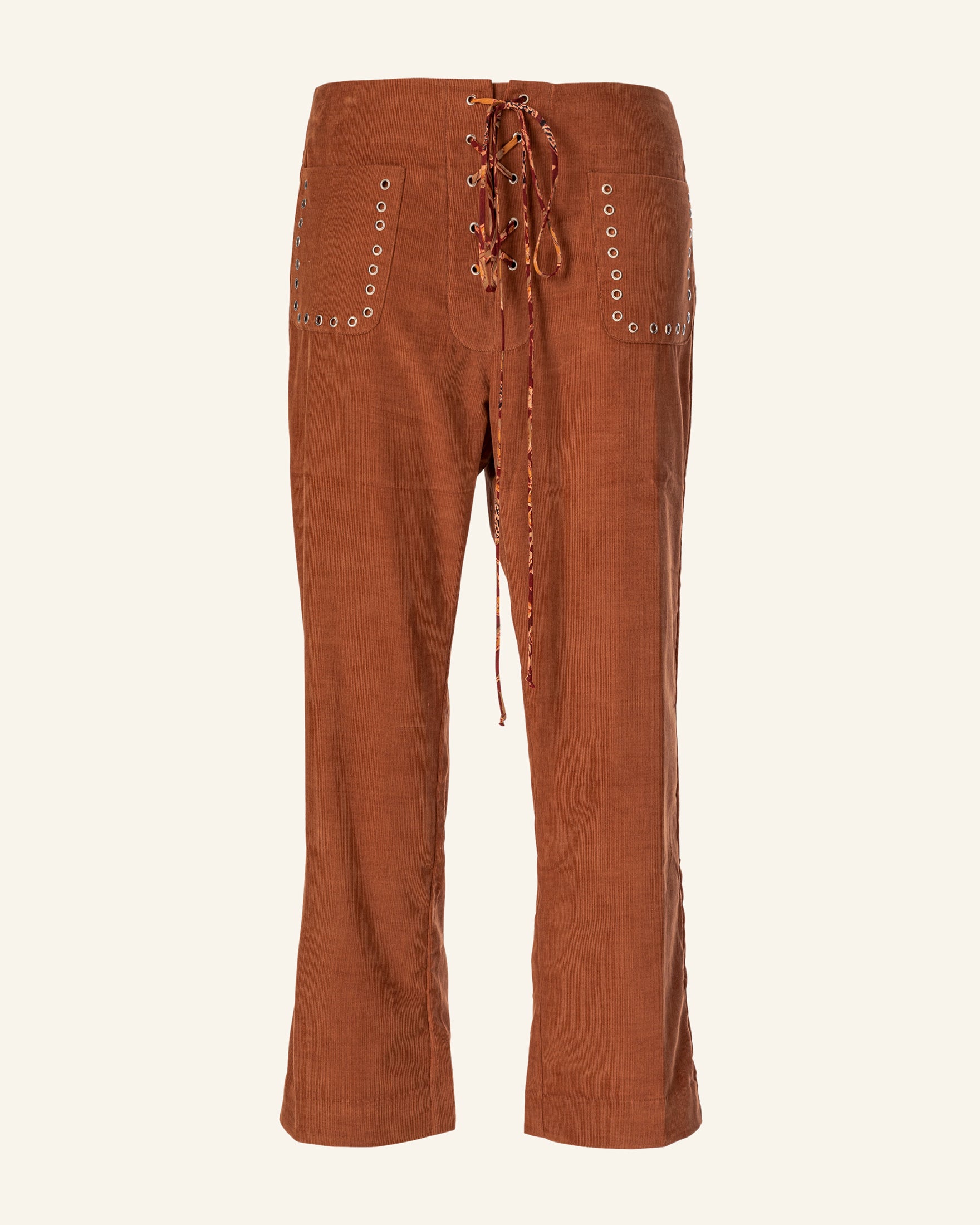 The Jodhpur Tawny Corduroy Pant showcases a rustic design with a lace-up front and side pockets adorned with metal eyelets, made from textured cotton corduroy for an authentic feel.