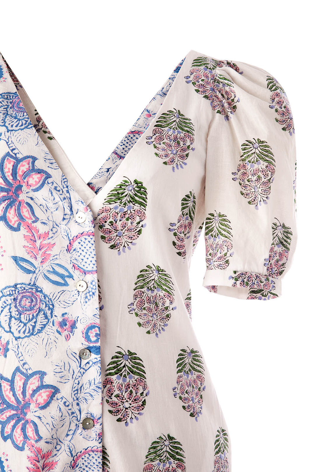 A close-up of the Fifty Fifty Bloom Dress reveals a unique combination of mixed prints: one side showcases a blue and pink floral pattern, while the other highlights a green and purple botanical design. This hand block printed dress features puffed short sleeves and button details.