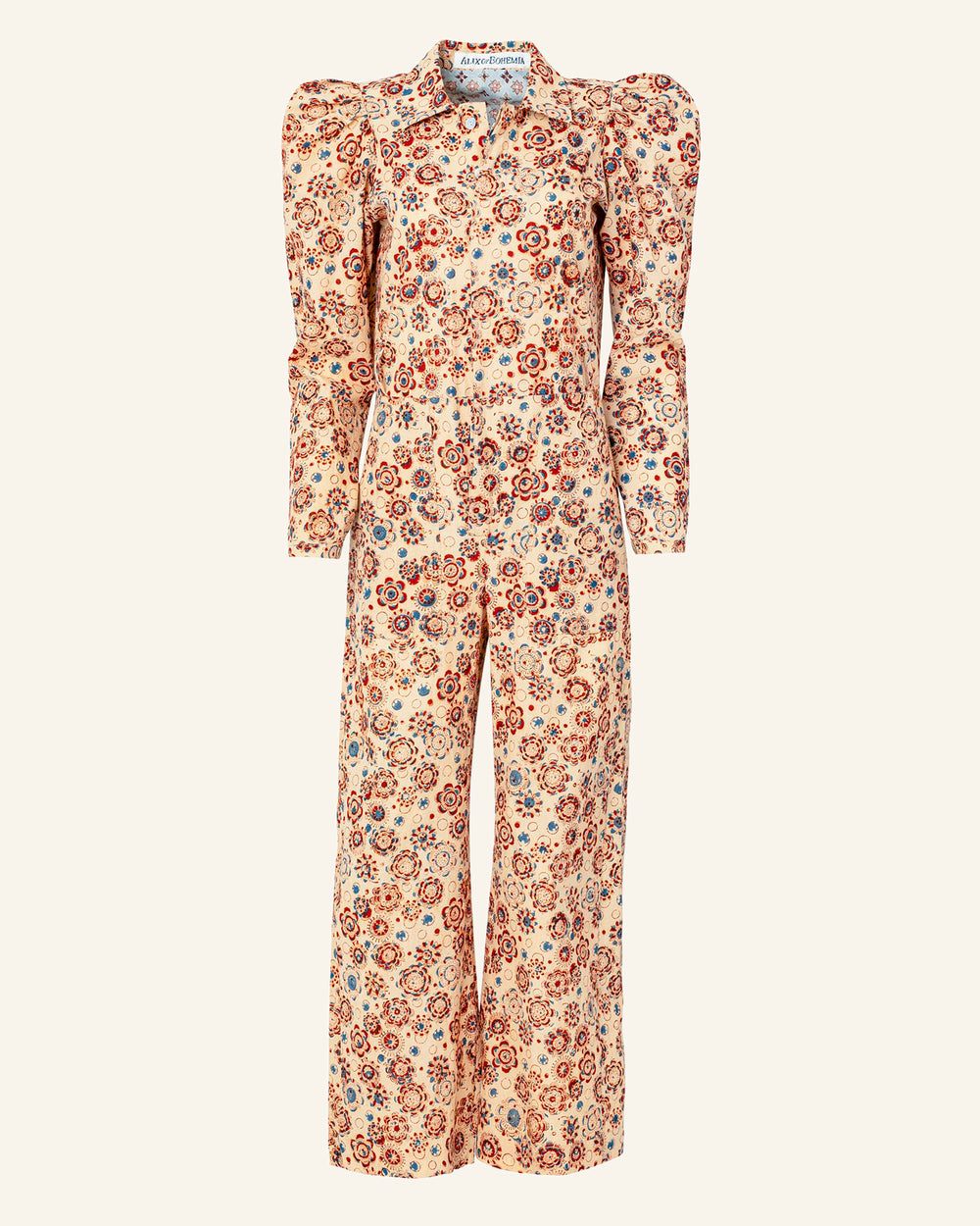 Introducing the Remy Juniper Jumpsuit: This exquisite piece is crafted from hand-printed cotton and features long sleeves with puffed shoulders. It showcases a stunning floral pattern in shades of red, orange, and blue against a light beige backdrop. Designed with a fitted waist and wide legs, it offers an elegant silhouette perfect for any occasion.