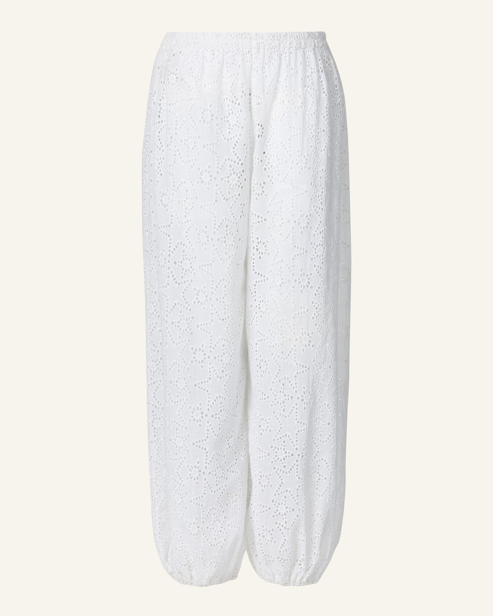 Introducing the Laure Star Anglaise Pant: white lace pants featuring an elasticized waist and cuffs, adorned with a detailed cut-out pattern. These lightweight, semi-transparent pants are made from delicate cotton eyelet for a breezy, elegant appearance.