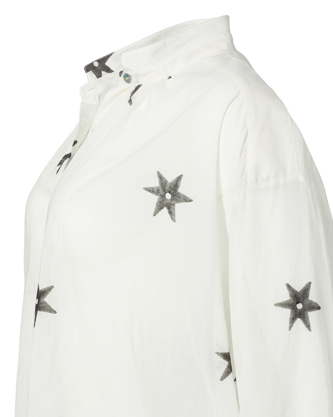 Introducing the Kiki Stargazer Blouse: a white button-up shirt featuring elegant black star patterns, expertly crafted from hand-printed cotton using traditional methods, and finished with exquisite Mother of Pearl buttons.