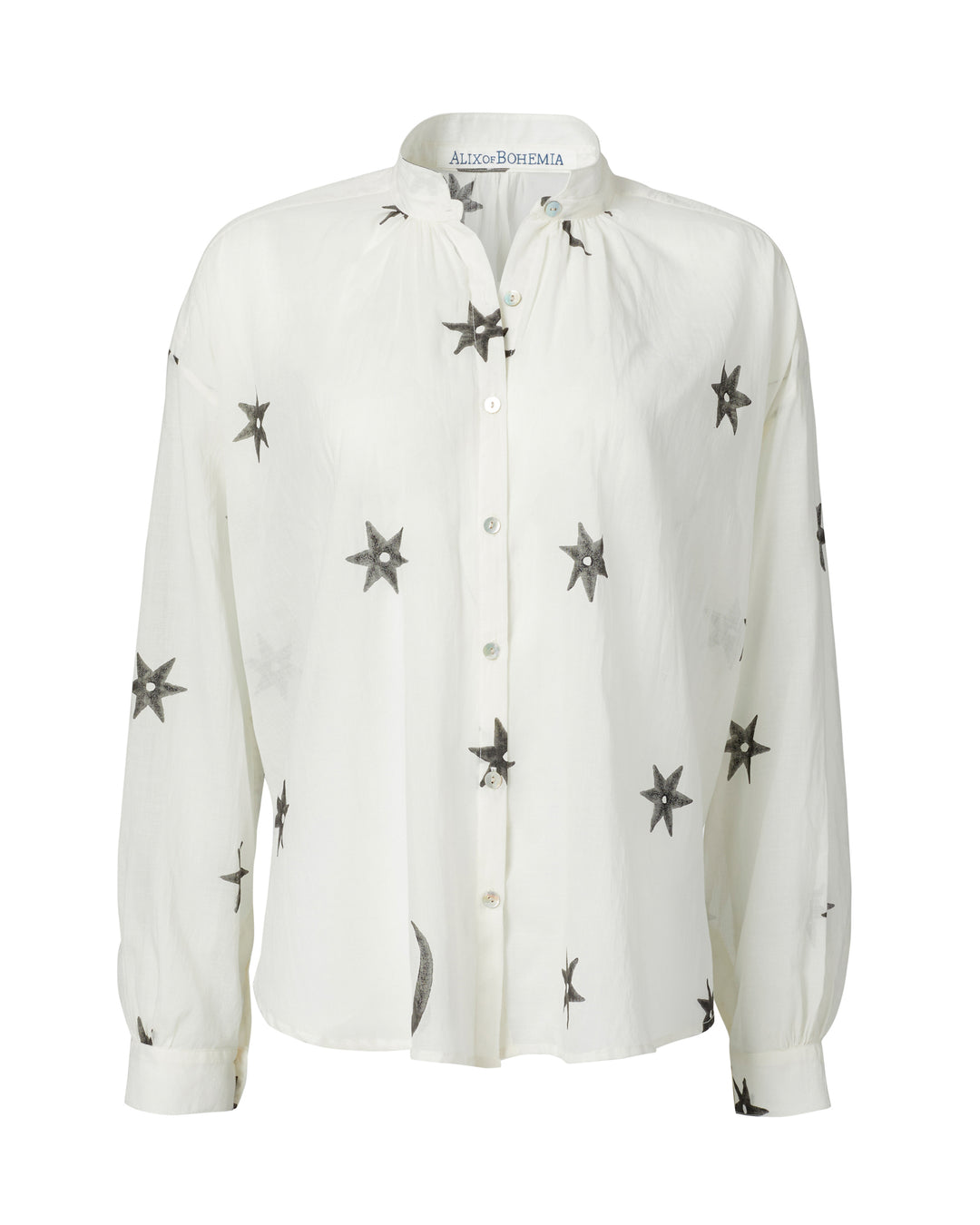 Introducing the Kiki Stargazer Blouse, featuring a white base with black star patterns, a button-up front, and crafted from hand-printed cotton using traditional methods. This elegant piece is adorned with exquisite Mother of Pearl buttons.