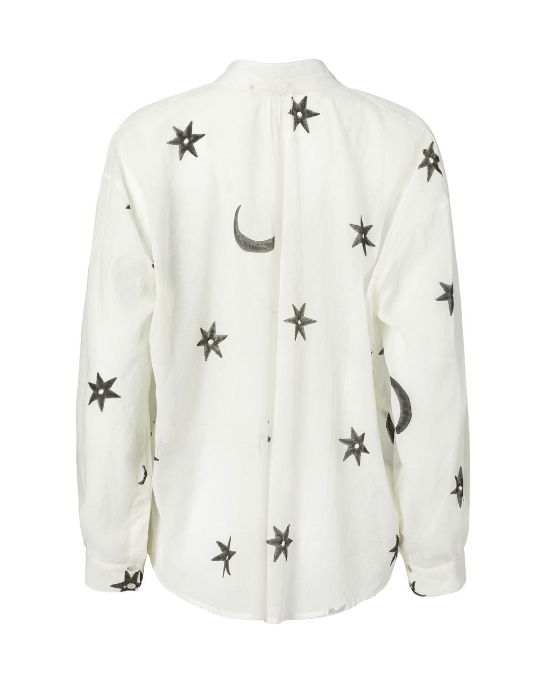 The Kiki Stargazer Blouse features a white long-sleeve design adorned with a pattern of black stars and crescent moons. It's crafted from hand-printed cotton using traditional methods and is finished with elegant Mother of Pearl buttons for added sophistication.