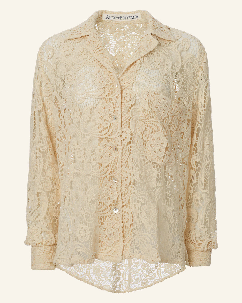 The Patti Ivory Floral Lace Shirt is a cotton lace blouse in beige, featuring long sleeves and a v-neck design. Adorned with a floral pattern and complete with a collar and front buttons, its high-low hem and slightly sheer fabric provide a relaxed fit suitable for any occasion.