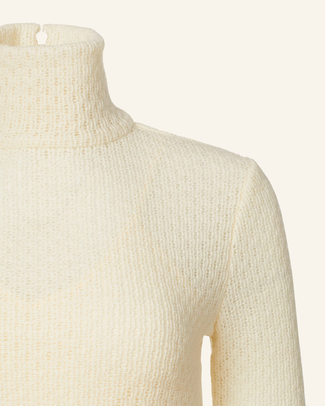 Close-up of the cream-colored Italian wool knitted Nona Marble Knit Dress, showcasing its texture and fabric. The dress's neckline and part of the shoulder are visible against a plain background.