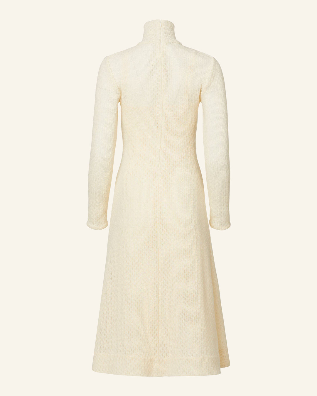 The Nona Marble Knit Dress is a long-sleeved cream-colored garment crafted from textured Italian wool. It features a high neckline and extends to mid-calf, showcasing a fitted waistline and an elegant A-line skirt with back detailing.