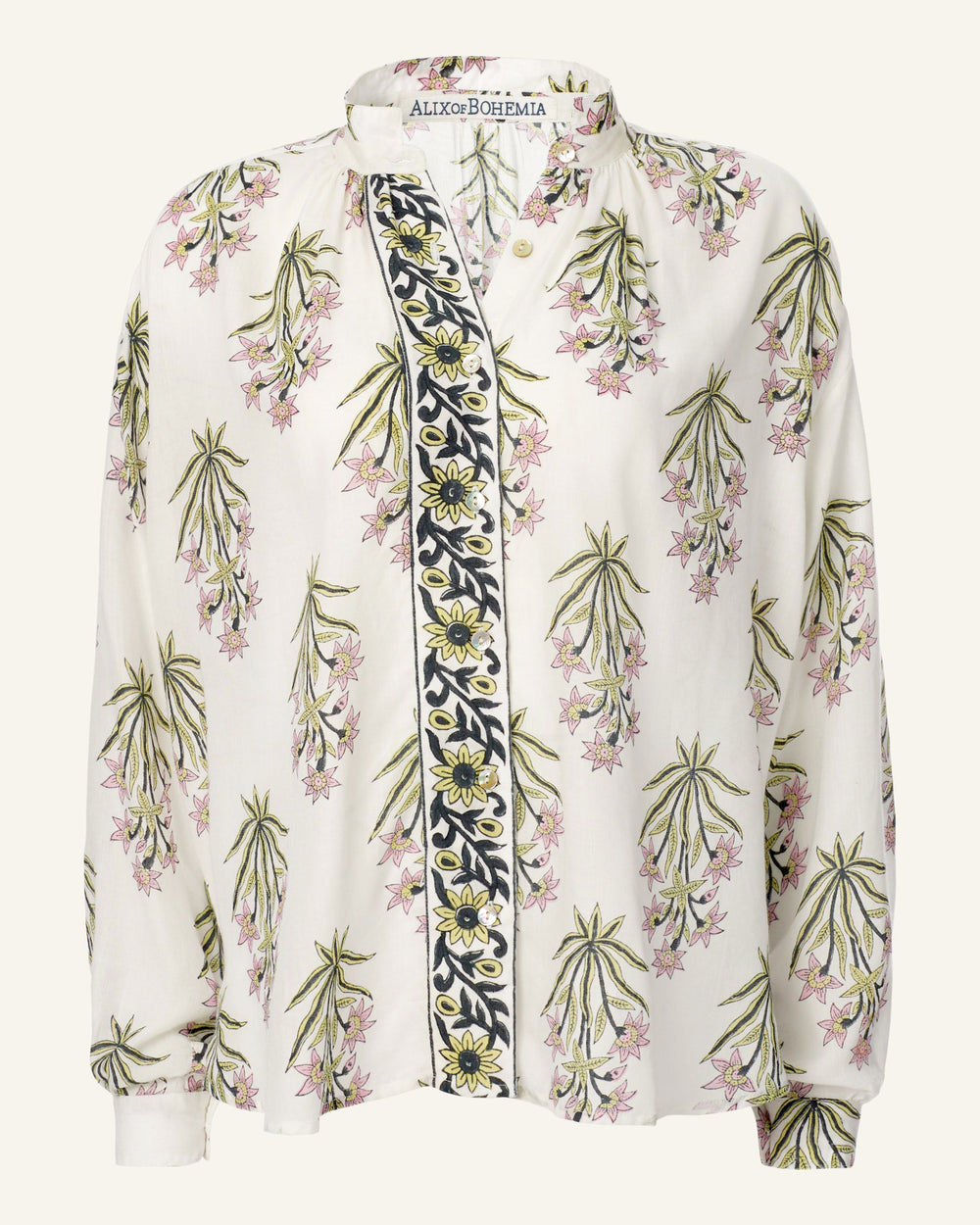 The Kiki Winter Lily Shirt is a traditional white blouse adorned with a pink and green floral print. It features a black and yellow floral strip running vertically down the center, completed with a Mother of Pearl button, while the "Alix of Bohemia" label is visible inside the collar.