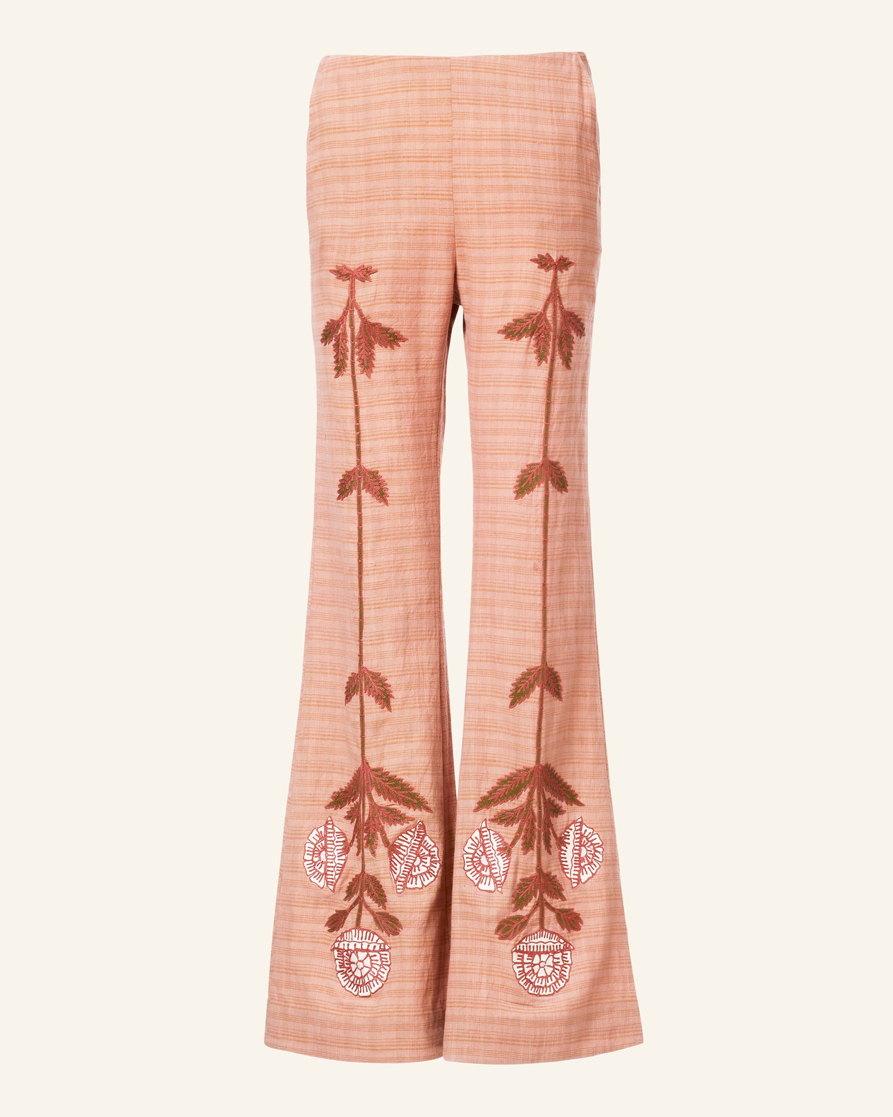 The Charlie Jute Embroidered Pant features a peach hue with flared ikat design, showcasing exquisite red and white floral motif embroidery cascading from the waistband to the hem. Its fabric has a subtle textured pattern, enhancing its elegance.