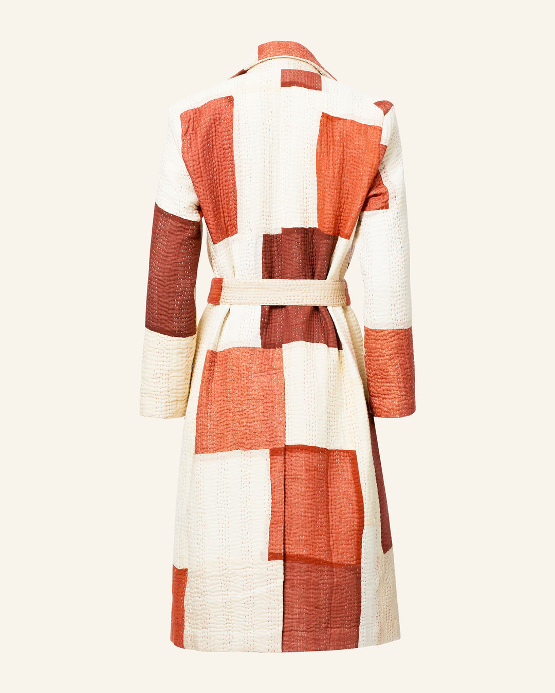 Showcased from the back, the Officer Almond Kantha Coat is a hand-stitched, multicolored patchwork coat featuring vibrant red, orange, and cream tones made from recycled silk.