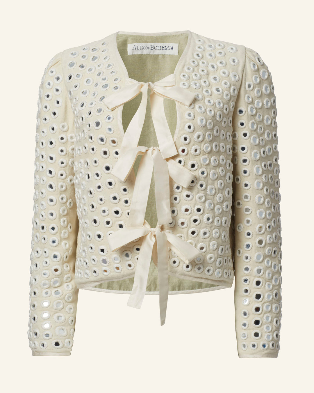 Meet the Pasha Frosted Mirror Jacket: a cream-colored knitted cardigan adorned with circular cutouts and exquisite mirror work. It features a V-neck, long sleeves, and three delicate light yellow ribbon ties on the front, offering an elegant touch that feels handcrafted.