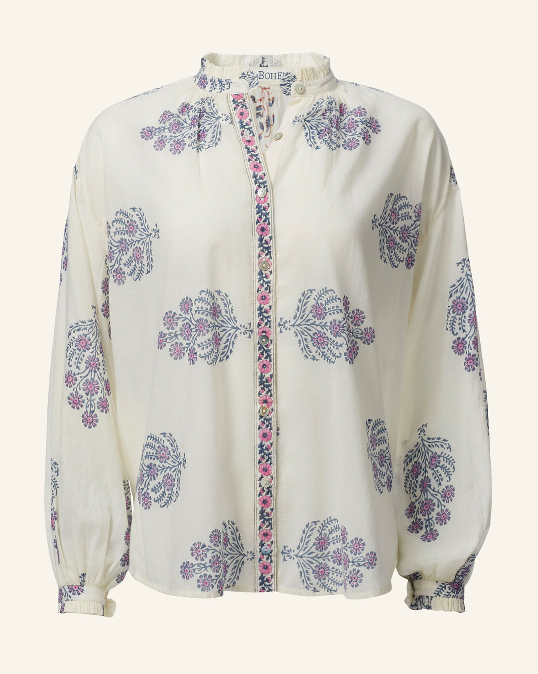 The Poet Freesia Phlox Blouse features a cream hue with long sleeves adorned with purple floral patterns and a multicolored trim along the buttoned front. Its slightly ruffled neckline adds vintage charm, while the lightweight fabric ensures comfort.