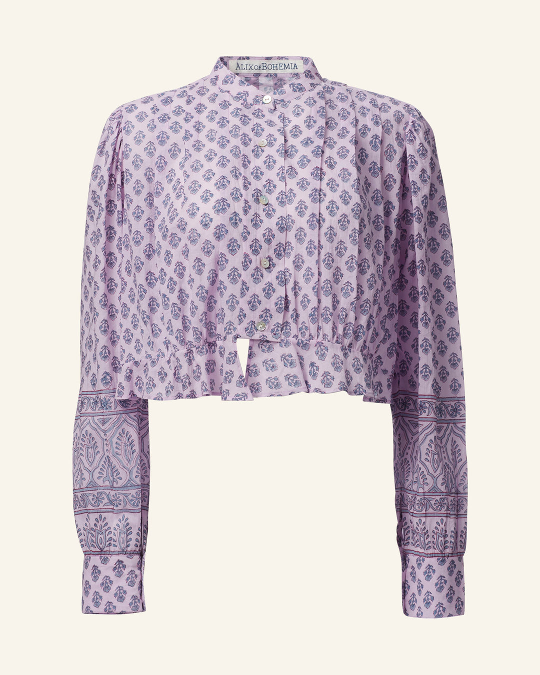 The Ryland Lilac Bhutti Top is a long-sleeve cropped blouse featuring a lavender floral print in a Victorian silhouette. It includes a band collar and buttoned cuffs, adorned with intricate designs on cotton voile.