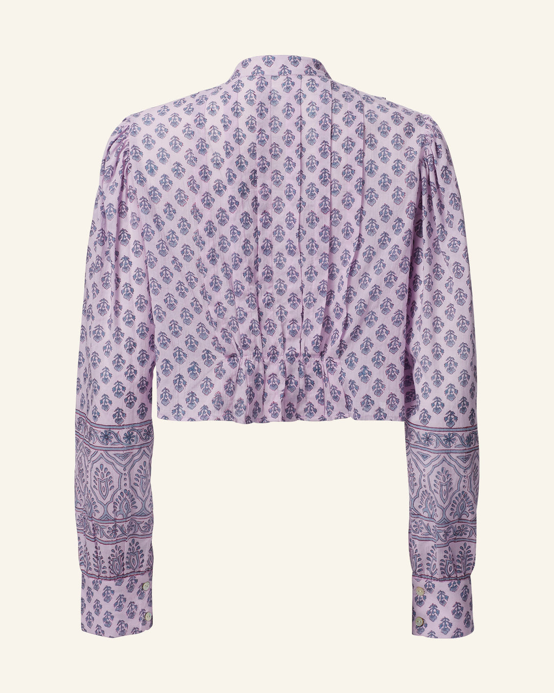 Introducing the Ryland Lilac Bhutti Top: This elegant long-sleeved blouse is crafted from cotton voile and showcases a sophisticated purple and white paisley pattern. Its high neckline complements the Victorian-inspired silhouette, while the design features subtle gathers at the shoulders and cuffs. Intricate border details adorn the sleeves and hem, adding an exquisite touch.