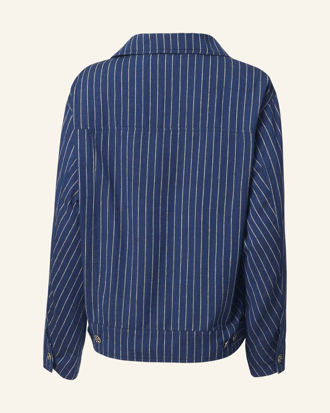 The Seba Luna Night Jacket is presented from the back, showcasing its blue color with white vertical stripes. Made from Khadi cotton, it features buttoned cuffs and a structured collar for a classic and casual appearance.