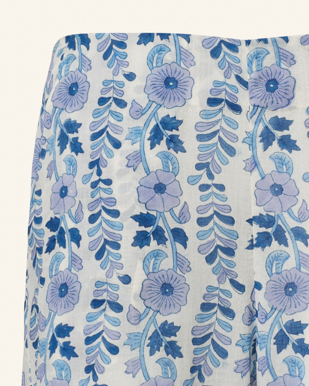 Close-up of the Charlie Iris Ivy Pant showcasing its hand-block printed fabric with a floral pattern. The design features blue and purple flowers, trailing ivy motifs, and green leaves on a light background, arranged in vertical lines.