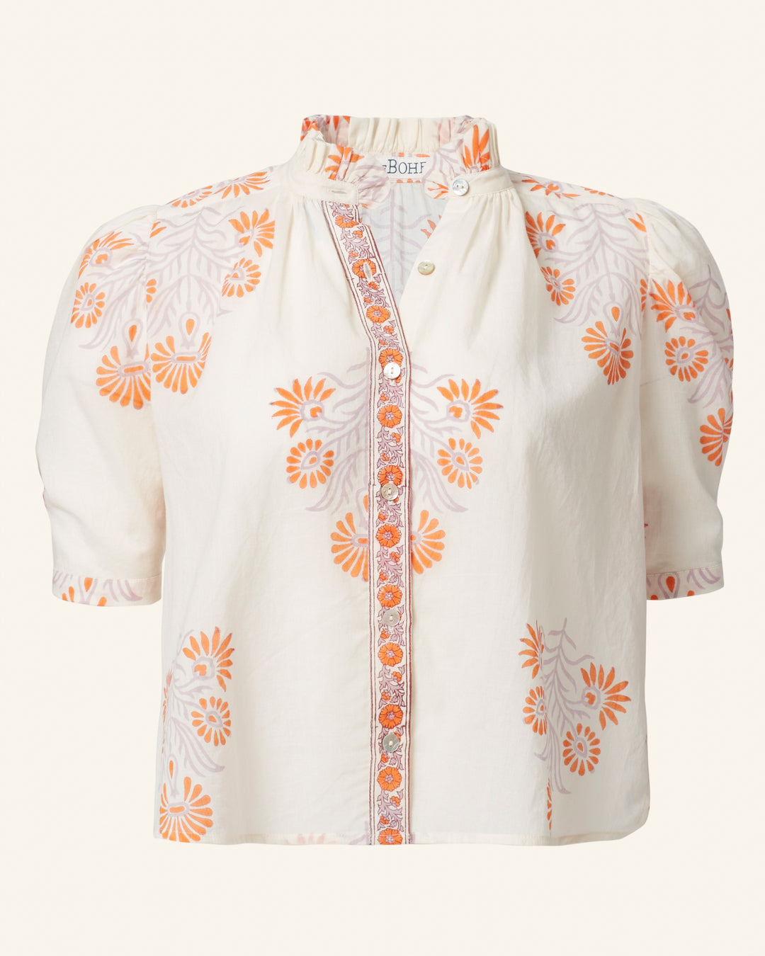 The Winn Papaya Aster Shirt is a vintage-inspired white blouse adorned with short puff sleeves and an orange floral pattern. Featuring decorative buttons on the front and a mandarin collar with subtle pleats near the neckline, this summer top adds an air of elegance to your sunny days.