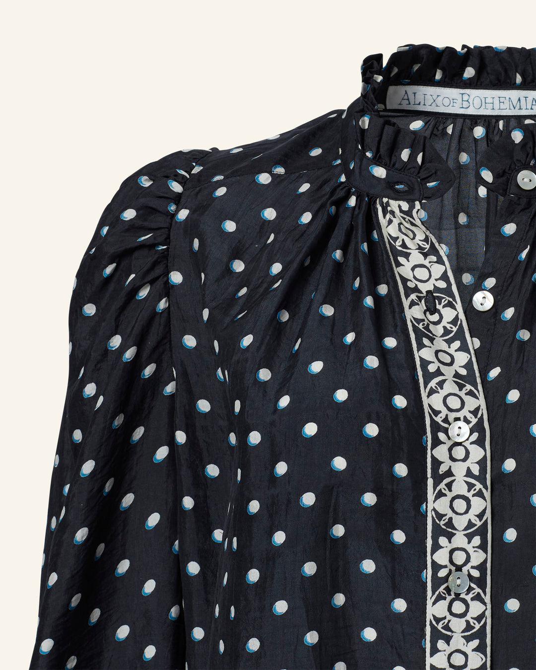 Close-up of a hand-block printed black Annabel Raven Dot Silk Shirt with white polka dots and intricate floral embroidery along the button placket. The label reads "ALIX of BOHEMIA.