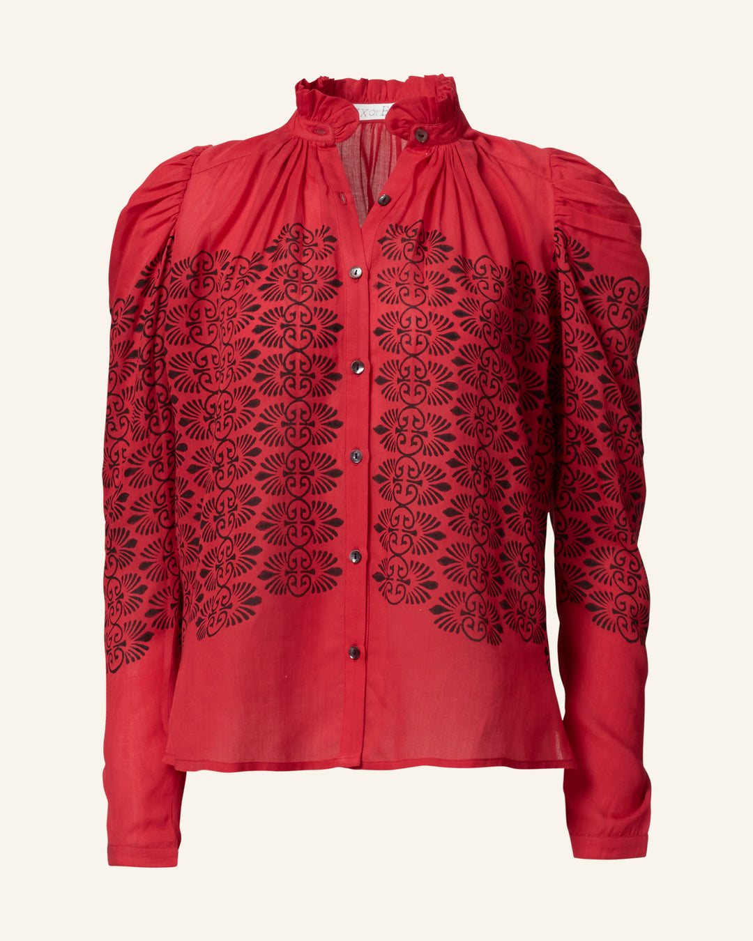 The Artemis Cherry Trellis Shirt is a vintage-inspired red blouse made from soft Tencel, adorned with intricate black embroidery in floral and geometric designs. It boasts a high collar, button-down front, and elegantly puffed long sleeves.