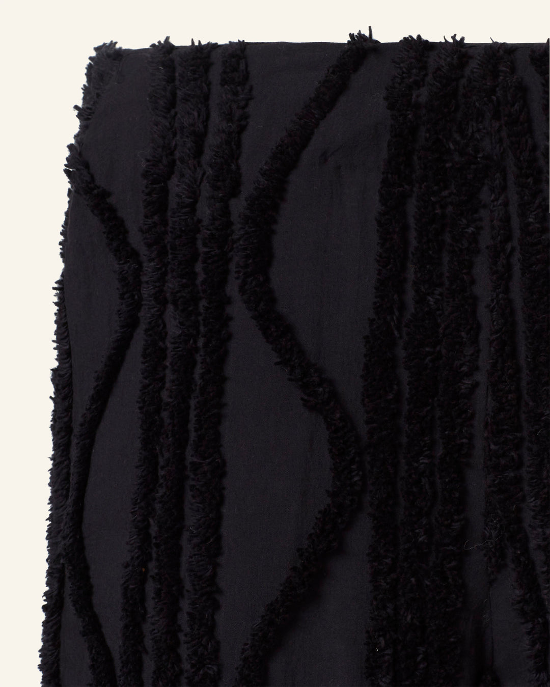 A close-up of the Charlie Onyx Shag Pant shows its black fabric with textured shag and vertical wavy lines in a soft, fuzzy material, beautifully contrasting against the light background.