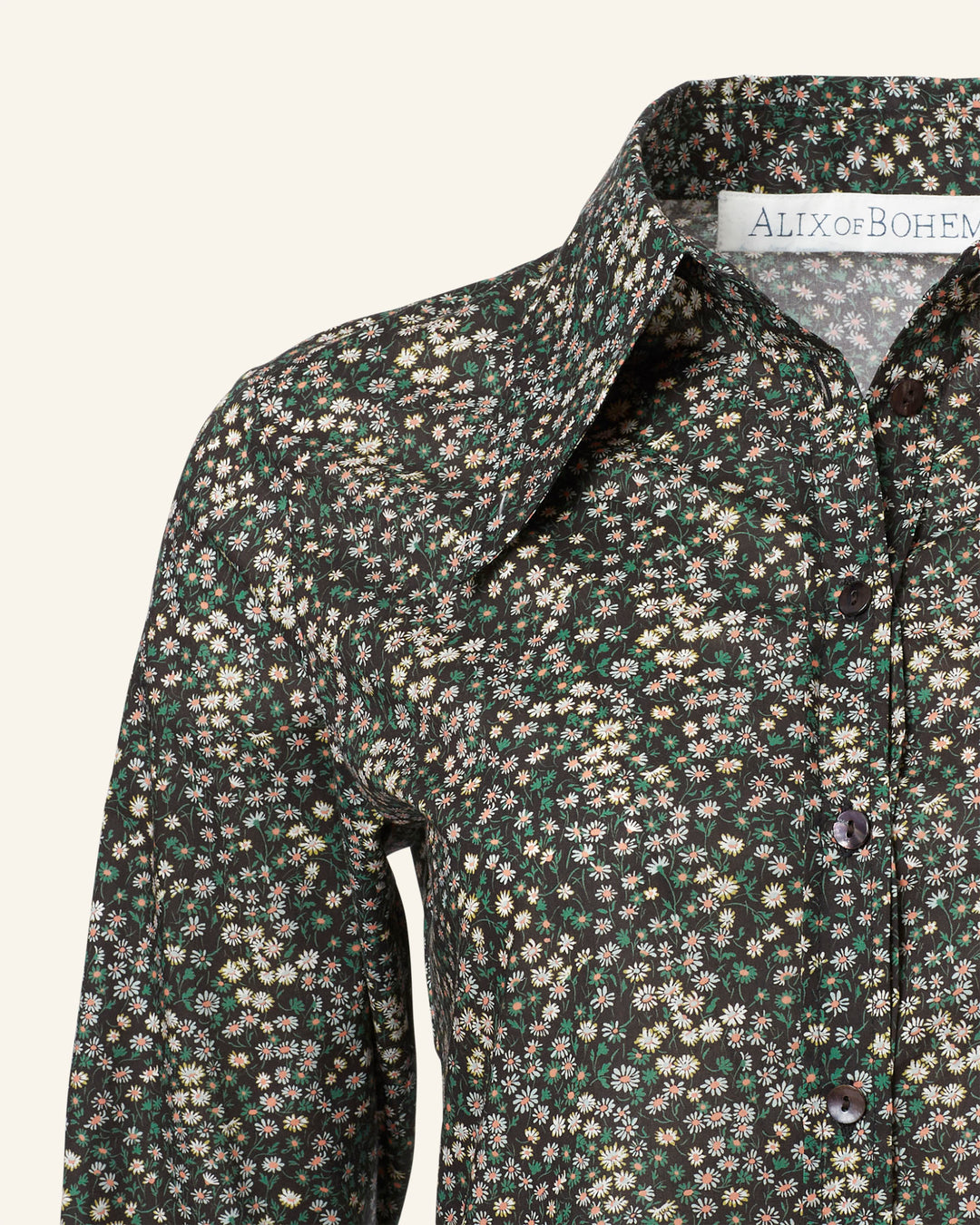 Close-up of the Dolly Moonflower Shirt, a vintage-inspired piece showcasing a floral design with small flowers in various colors against a dark background. The pointed collar enhances its Liberty-print charm, and the label reads "ALIX of BOHEMIA.