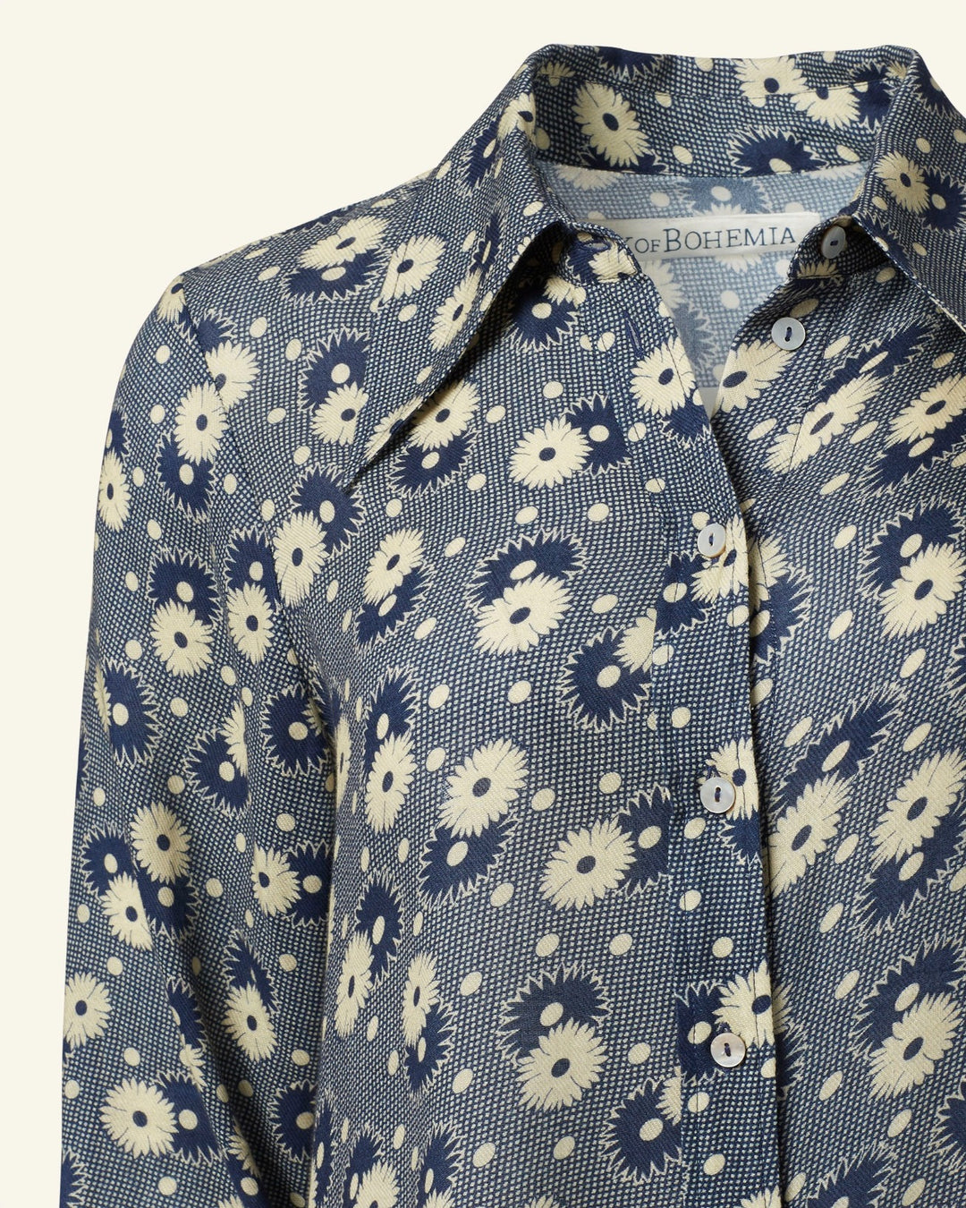 Close-up of the Dolly Navy Daisy Shirt, a vintage-inspired piece in navy blue adorned with a retro floral pattern, complete with buttons and a collar.