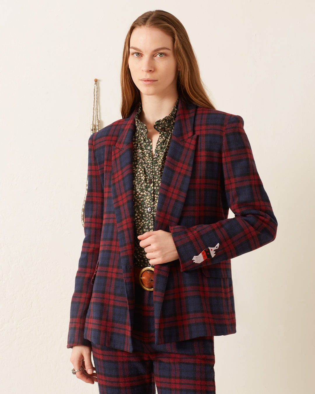 A person wearing the Dree Berry Plaid Blazer, featuring a red and blue plaid pattern, pairs it with a patterned green shirt against a neutral background, exuding confidence with its sophisticated cotton-silk lining.