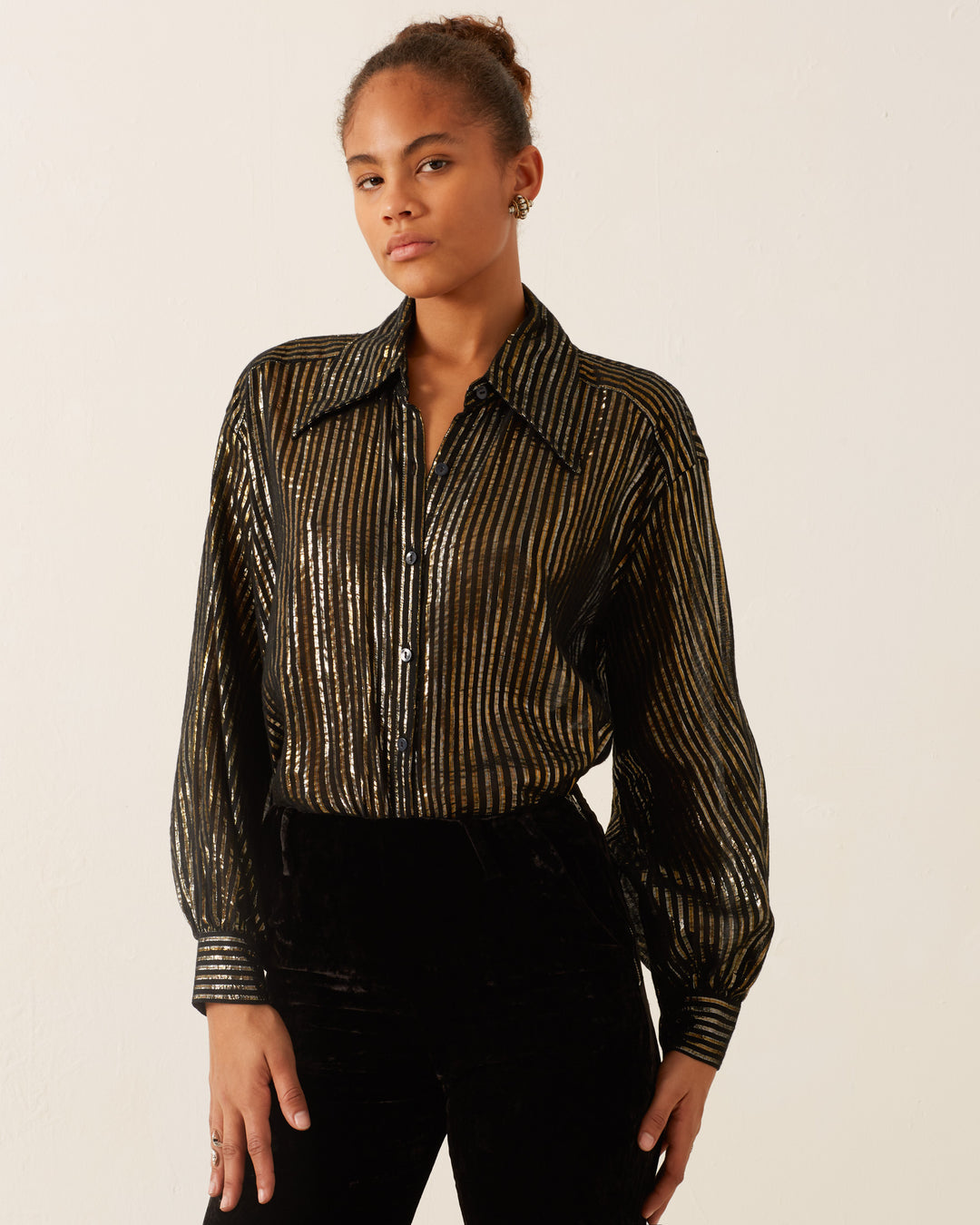 A person wearing the Emery Moonlight Shirt, featuring a vintage-inspired design with metallic stripes, paired with dark pants, standing against a plain background.