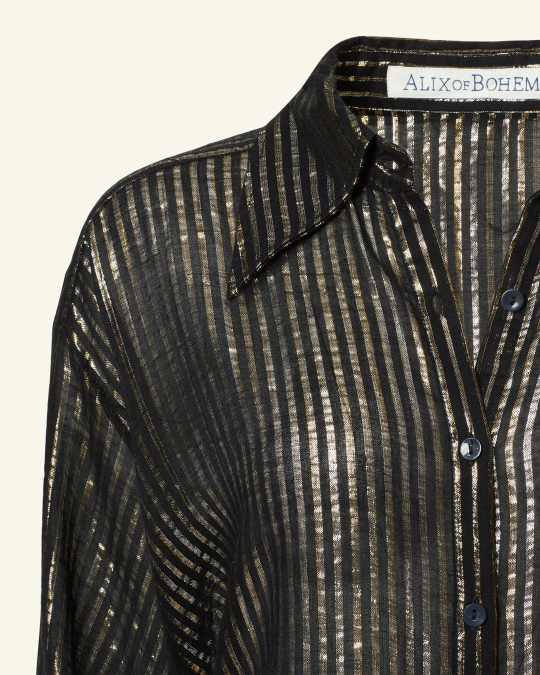 Close-up of the Emery Moonlight Shirt, a sheer black button-up featuring metallic vertical stripes and a '70s-style wing collar, with the "ALIX of BOHEMIA" label visible at the neckline.