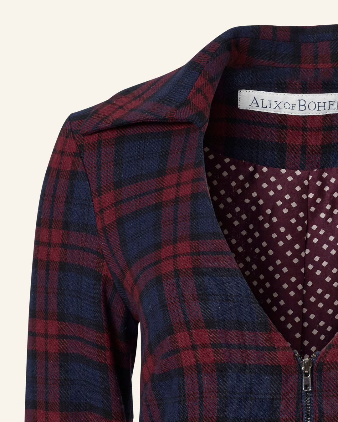 Close-up of a red and blue plaid jumpsuit with a wide collar and zipper, showcasing the "Alix of Bohemia" tag and enriched with a cotton-silk lining that adds luxury.