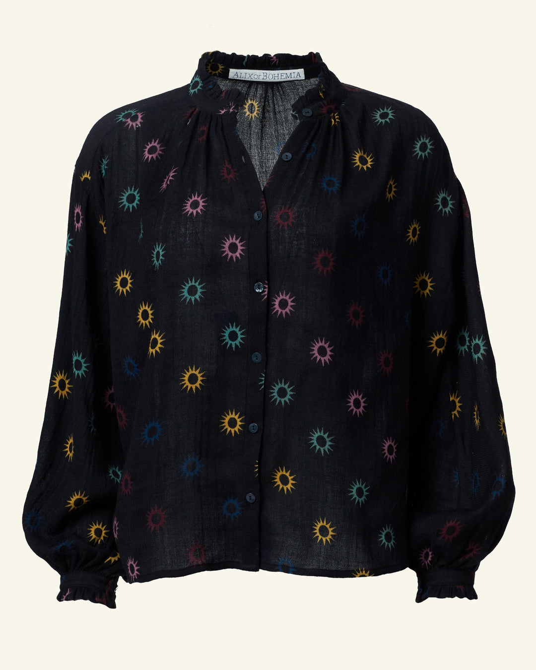 Introducing the Poet Evening Star Blouse, a stylish black top with long sleeves adorned in a lively celestial print of blue, red, yellow, and green. The repeating sunburst pattern infuses this star motif blouse with an energetic burst of color.