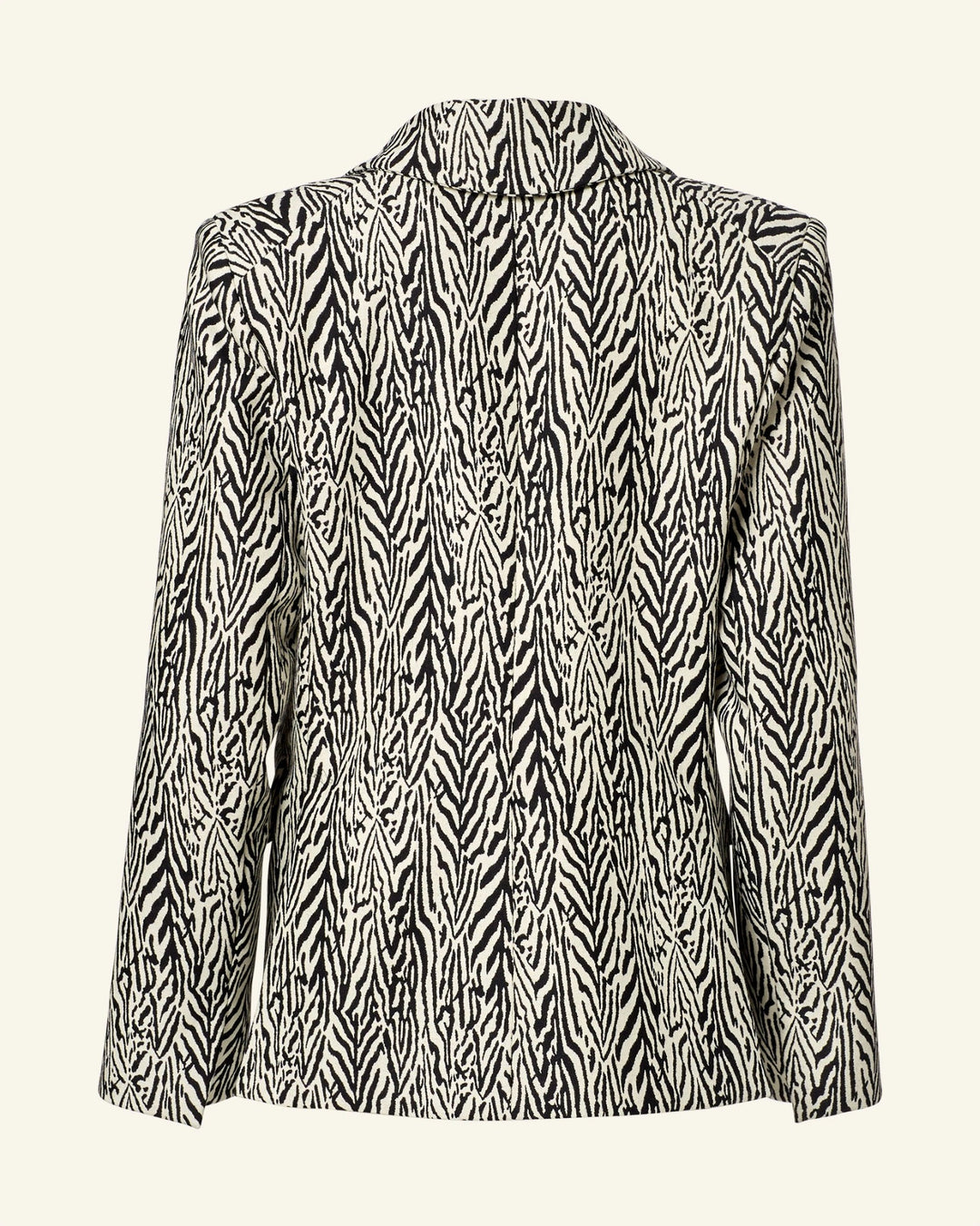 Back view of the Dree Zebra Blazer featuring a black and white abstract pattern made from virgin wool. It has a structured fit with peak lapel, no visible buttons or pockets, set against a light beige background.