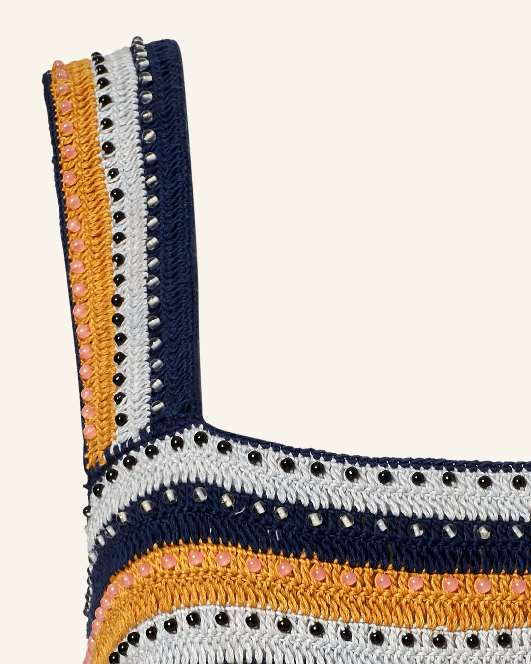 Close-up of the Mia Mirage Crochet Top, featuring horizontal stripes in navy, white, yellow, and pink. Small black and multi-colored beads adorn the edges for textured appeal. The fabric showcases a repeating pattern.