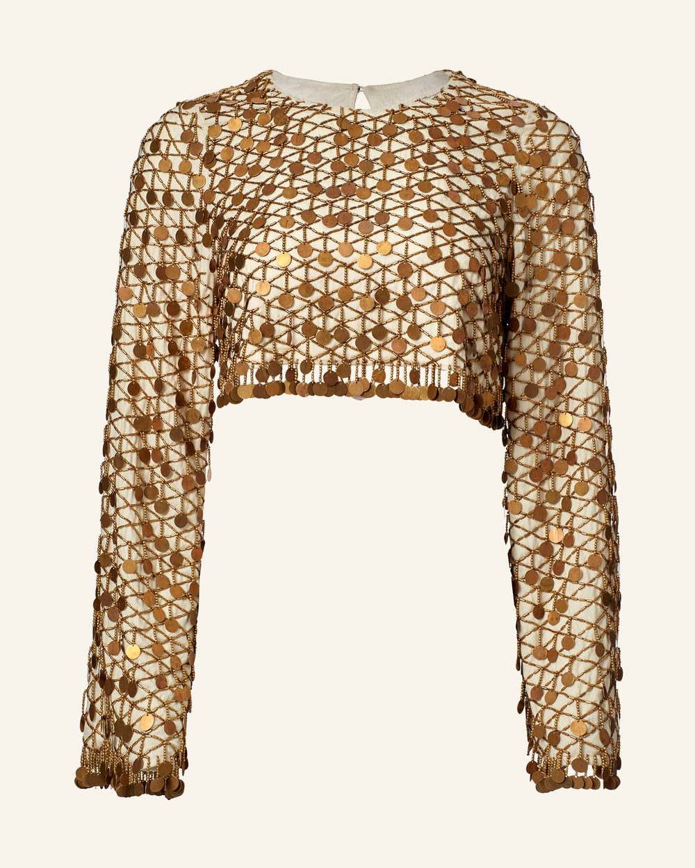 The Nina Whitegold Coin Top is a long-sleeved, hand-embellished cropped top with gold geometric sequins on sheer nude fabric.