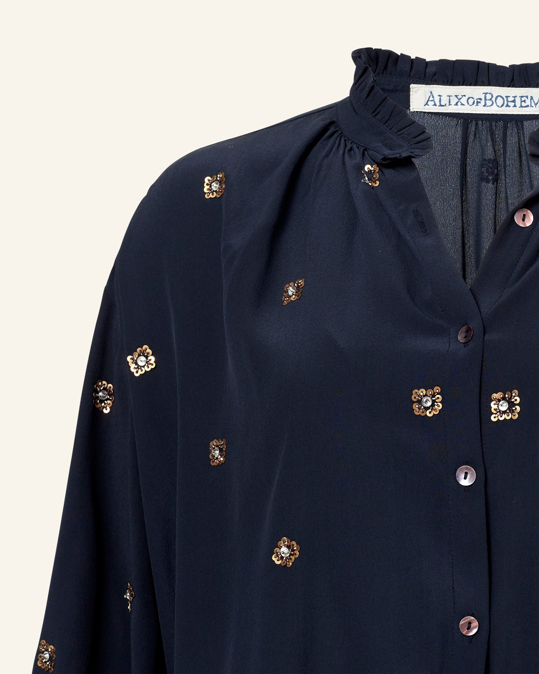 Close-up of the Poet Casino Night Blouse in dark blue silk featuring a ruffled collar, small floral embroidery with sequins, and buttons along the front. The "Alix of Bohemia" label is visible at the neckline, exuding vintage-inspired charm.