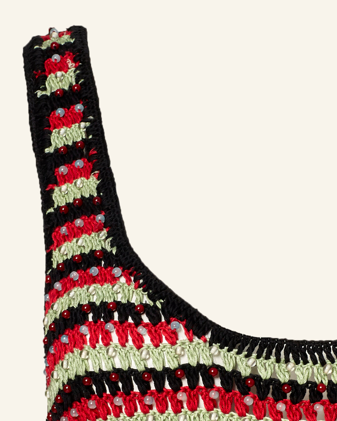 Close-up of the Tyler Poinsettia Crochet Dress, a striped knit design in black, red, and green. Ideal as a beach cover-up, it is adorned with small decorative pearl-like beads throughout.