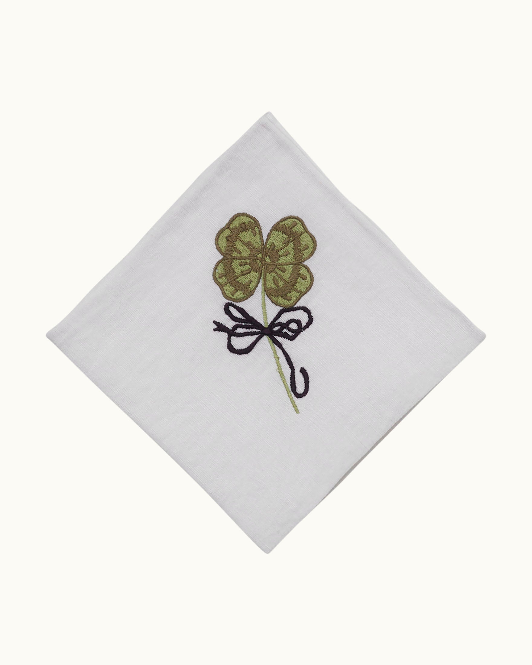 Cai Lucky Love Handkerchief crafted from a white linen-cotton blend, featuring a hand-embroidered green four-leaf clover, elegantly tied at the center with a black bow.