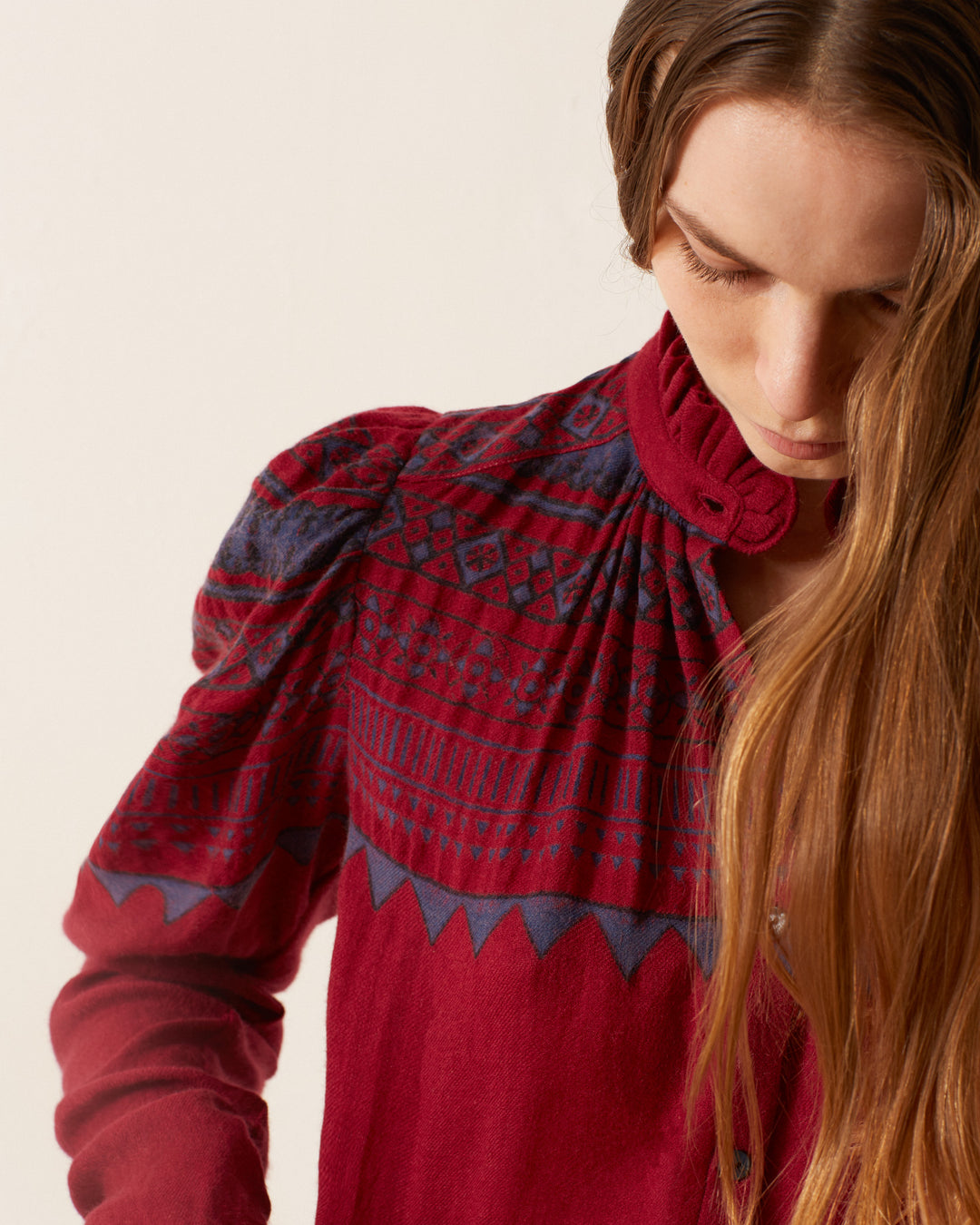 A person with long hair wearing the Artemis Plum Fairisle Shirt looks down against a plain background.