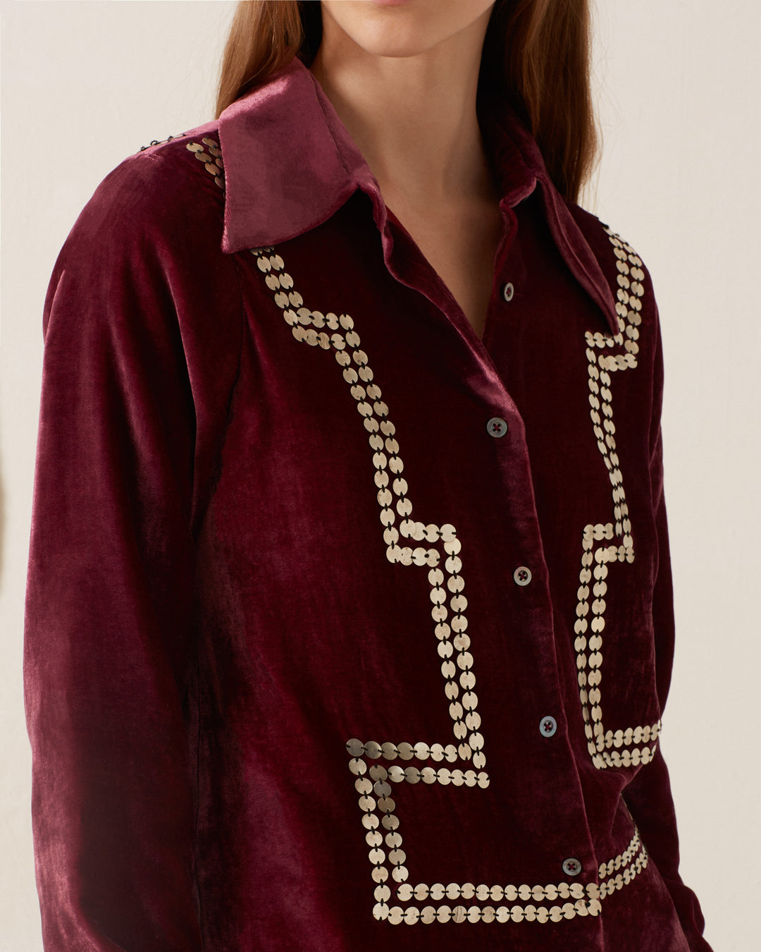 A person wearing the Dolly Plum Velvet Shirt in maroon, featuring decorative metallic studs along the front and collar, exuding a vintage-inspired charm.