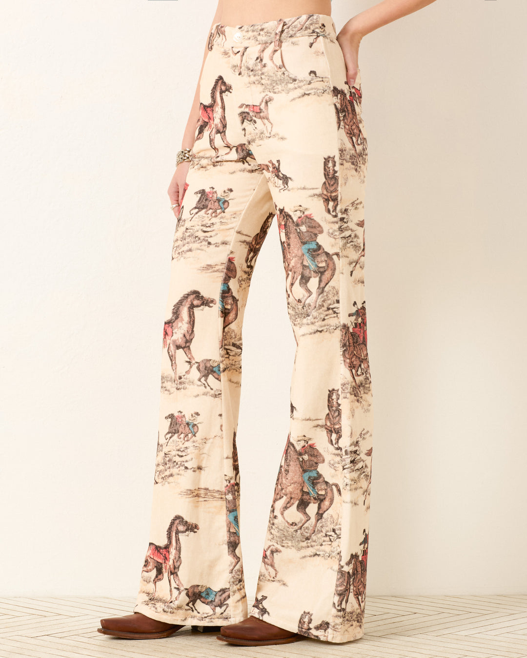 A person wearing Bunny Canyon Cowboy Jeans with a Western cowboy and horse print, paired with brown shoes.