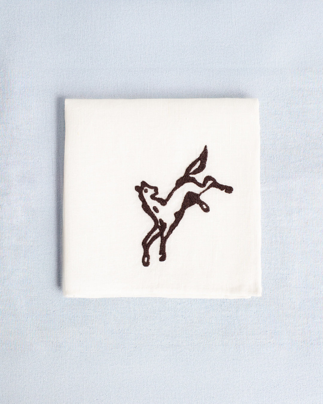 The Cai Bronco Handkerchief is a white linen-cotton accessory with a simple black embroidered prancing horse, shown on a light blue background—ideal as a western bronco handkerchief or good luck gift.