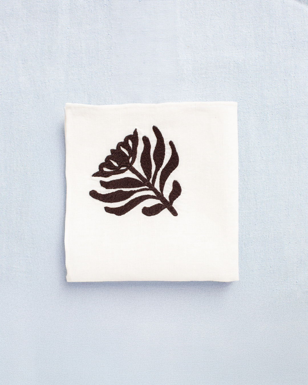 The Cai Cactus Flower Handkerchief is a white linen-cotton accessory featuring a brown cactus flower motif, perfect for adding a subtle Western-inspired accent.