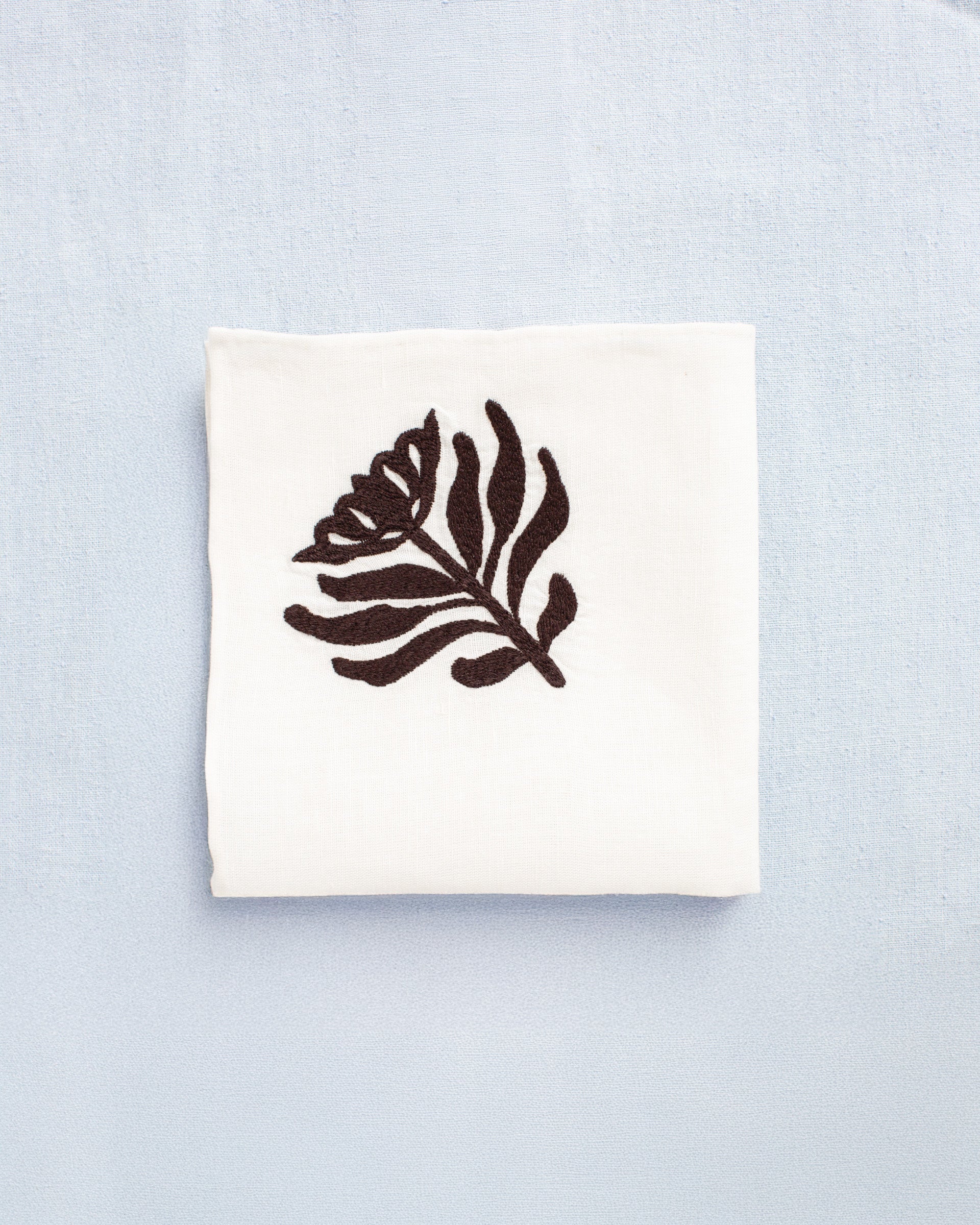 The Cai Cactus Flower Handkerchief is a white linen-cotton accessory featuring a brown cactus flower motif, perfect for adding a subtle Western-inspired accent.