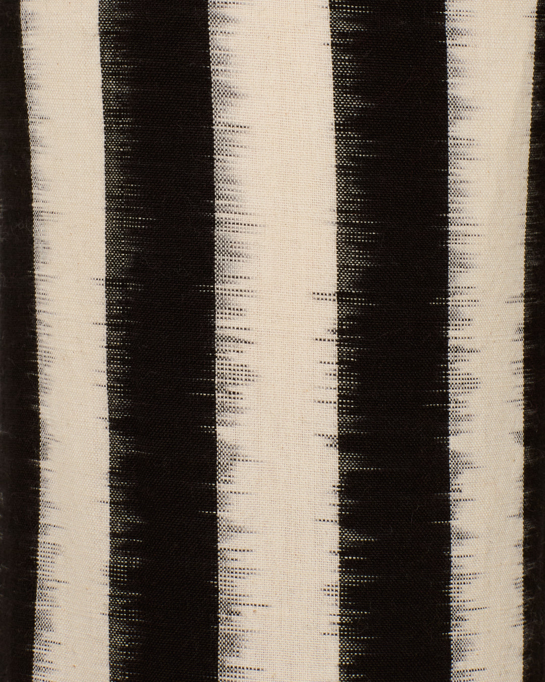 The Charlie Coal Stripe Pant features vertical black and off-white stripes with a textured, ikat-inspired look—ideal for a relaxed, flared leg silhouette.