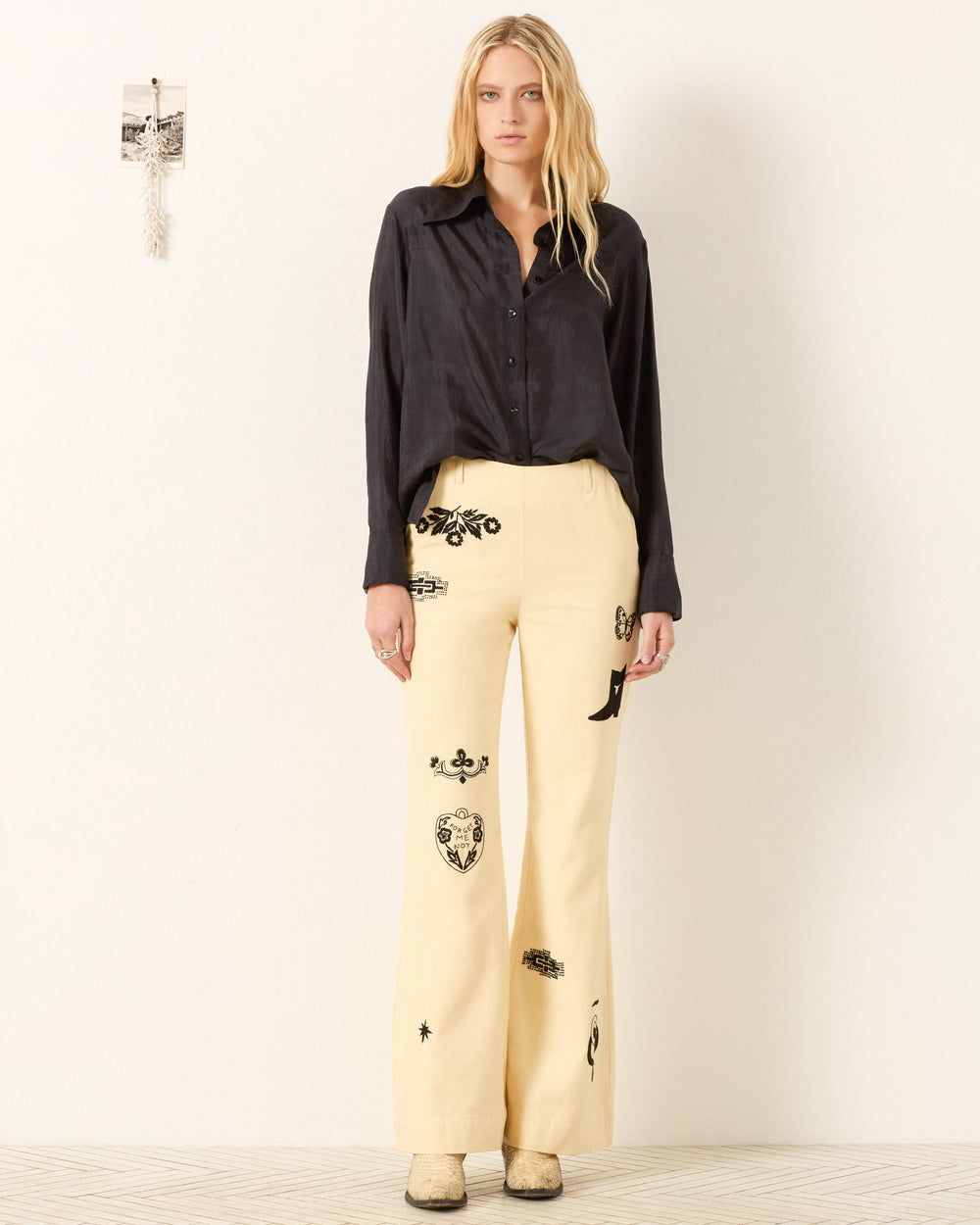 A woman stands in a room, wearing the Dana Onyx Silk Shirt with vintage-inspired style and elegant French cuffs.