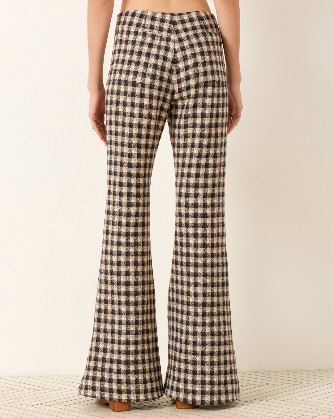 Person facing away from the camera wears the Farah Trail Dust Pant, a high-waisted beige and dark blue plaid style made from luxurious Italian virgin wool with a subtle bell-bottom flare.