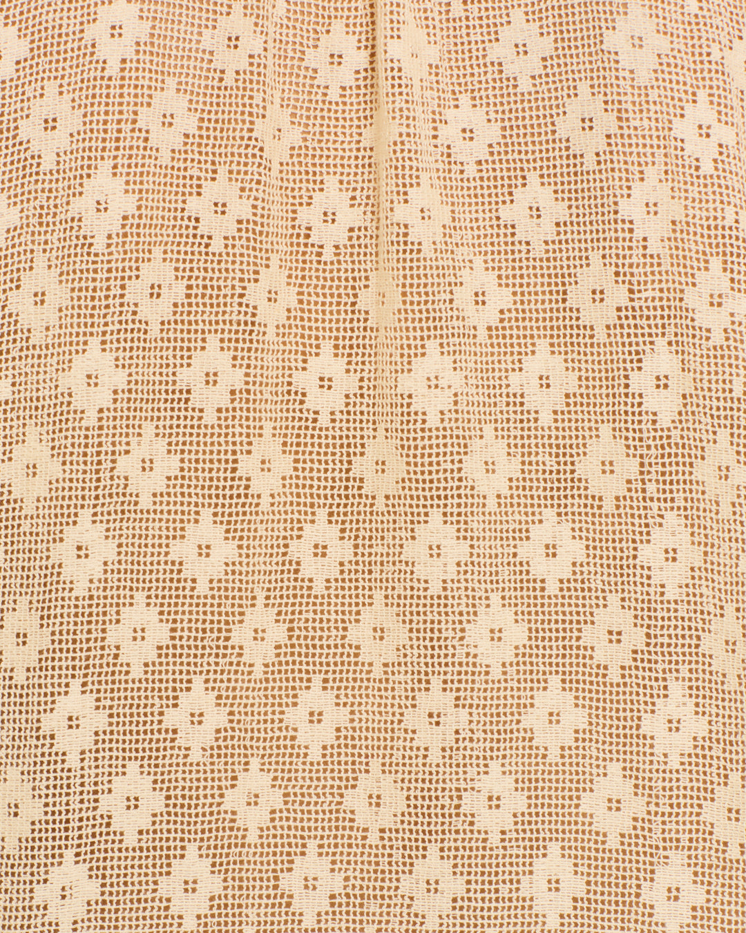 Close-up of the Mazie Antique Bone Lace Shirt's beige cotton fabric, showcasing a diamond and cross pattern with small, evenly spaced holes and a vertical seam—a perfect nod to ’70s dandy style.
