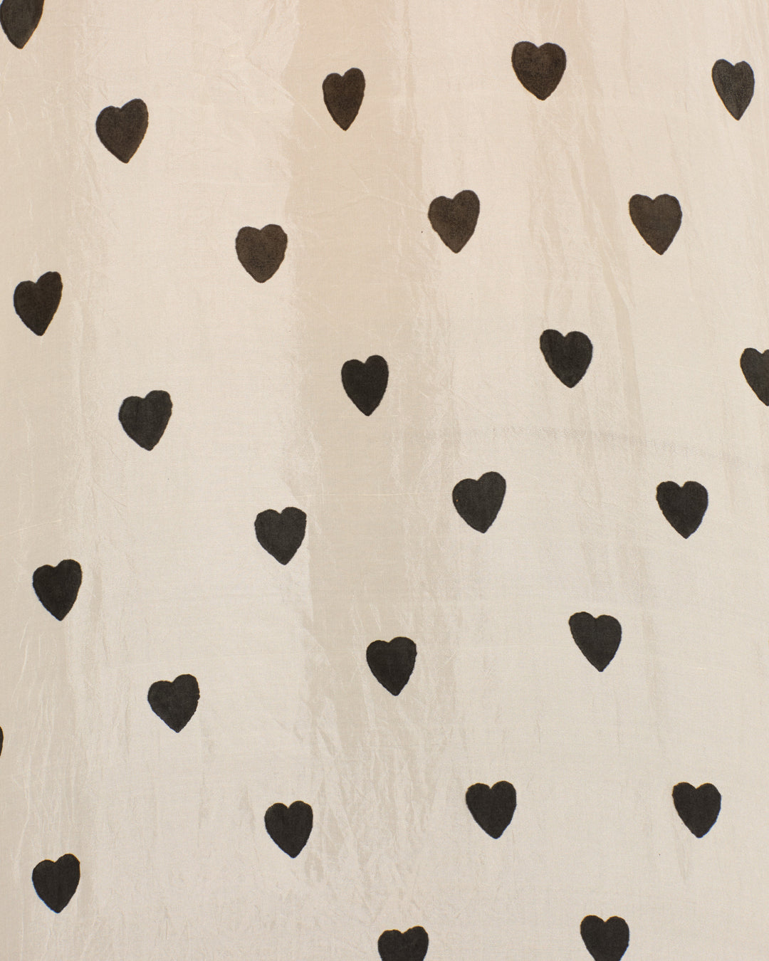Black hearts in a grid pattern decorate the Mazie Onyx Heart Silk Shirt, set on light beige silk for a vintage 70s dandy-inspired look.