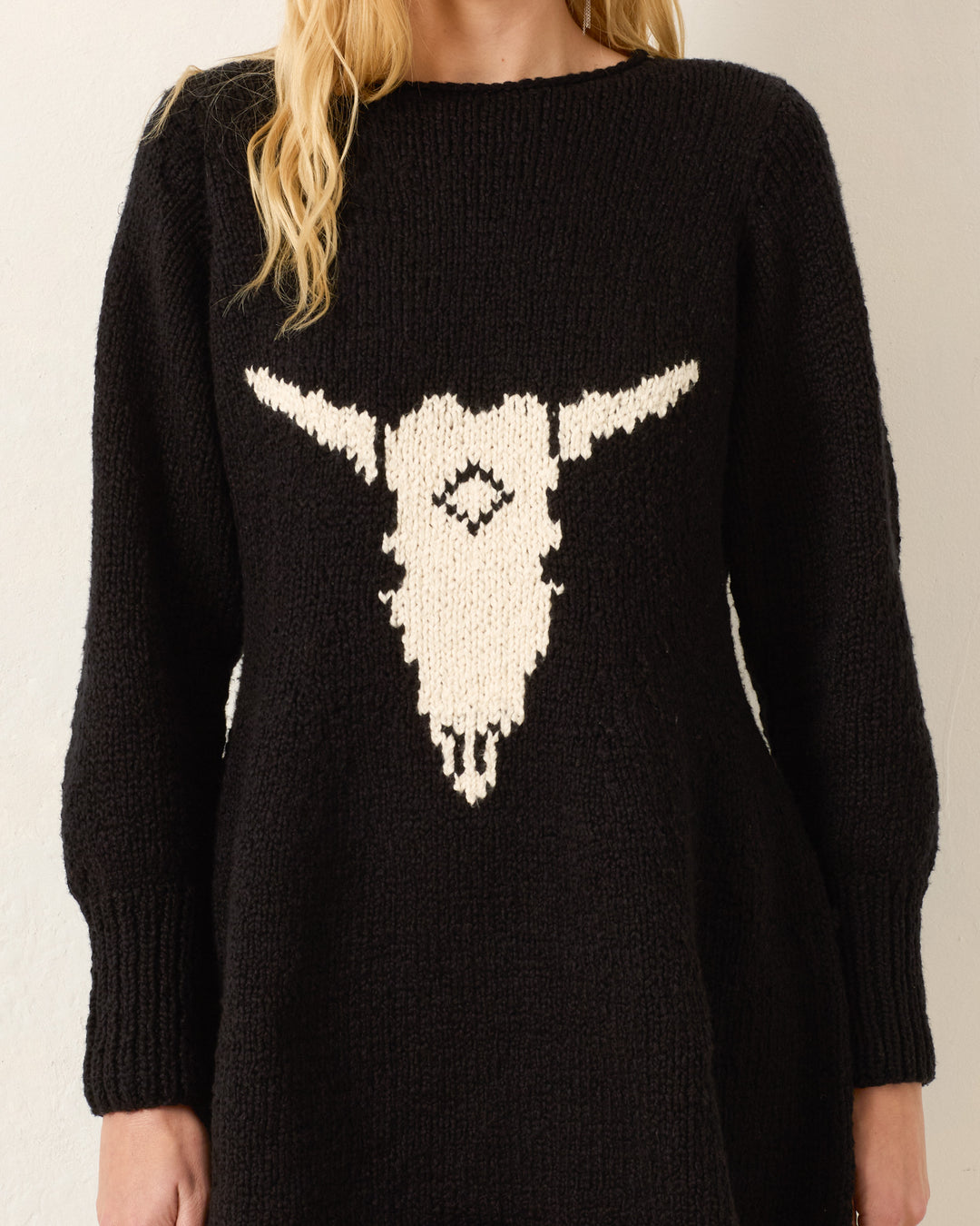 Person wearing the Renny Cow Skull Dress, a black sweater dress featuring a white bull skull graphic on the front. The person’s face is not visible.